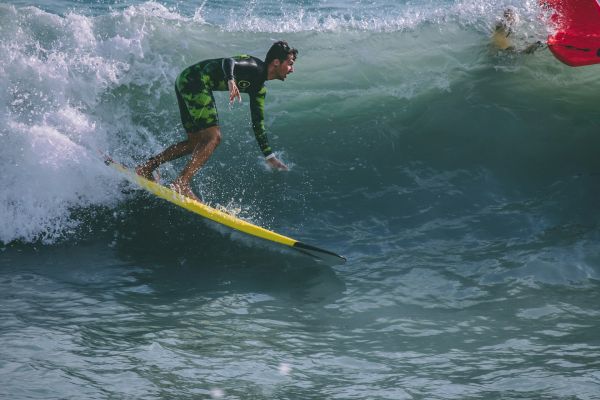 A person surfing on a wave with a yellow surfboard, wearing a wetsuit, surrounded by ocean water.